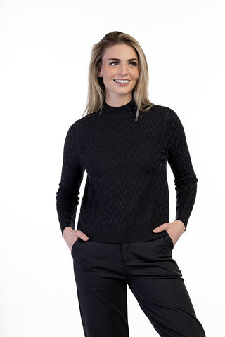 Model wearing a cable knit mock neck sweater with long sleeves and ribbed trim